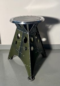 Das Projekt Aero 1946 kombiniert die Handwerksarbeit nach dem klassischen Flugzeugbau der 1940er Jahre mit dem Prinzip des Upcyclings. Das Material stammt in der Regel von Heckauslegern, Finne oder Elevatoren alter BELL-Hubschrauber. Die ultraleichten Hocker sind stylische Unikate und sehr belastbar. Die unterschiedlichen Farben, Beschriftungen und Nietlöcher verweisen auf die ursprüngliche Verwendung. Jeder Hocker ist auf der Unterseite mit dem passenden Typenschild versehen.