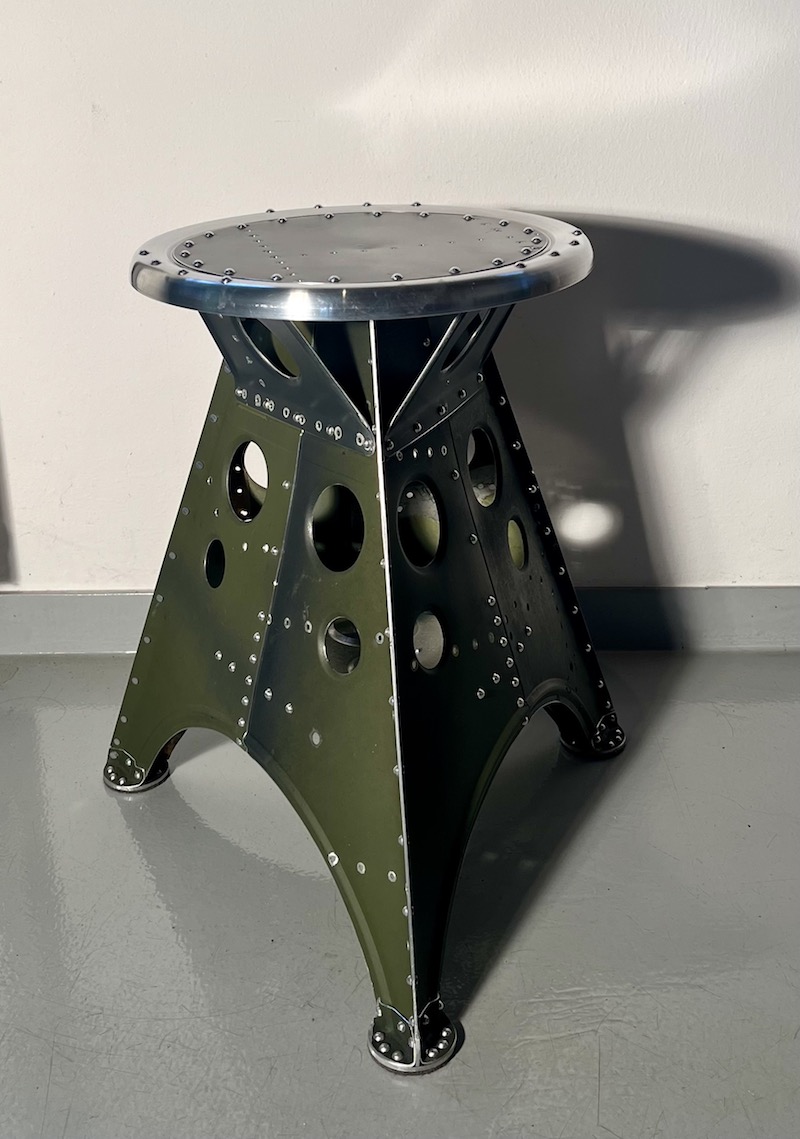 Das Projekt Aero 1946 kombiniert die Handwerksarbeit nach dem klassischen Flugzeugbau der 1940er Jahre mit dem Prinzip des Upcyclings. Das Material stammt in der Regel von Heckauslegern, Finne oder Elevatoren alter BELL-Hubschrauber. Die ultraleichten Hocker sind stylische Unikate und sehr belastbar. Die unterschiedlichen Farben, Beschriftungen und Nietlöcher verweisen auf die ursprüngliche Verwendung. Jeder Hocker ist auf der Unterseite mit dem passenden Typenschild versehen.