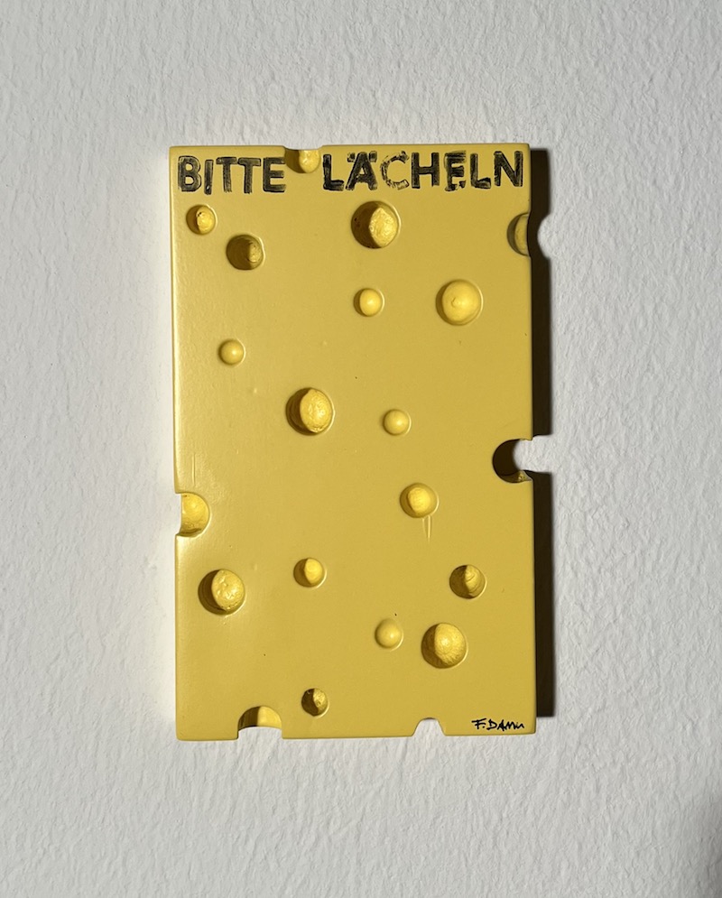 Frank Damm - "o.T. Käse" (10 x 16,5 cm) Dynamik, Licht und das pulsierende Leben unserer Zeit sind Frank Damms vorherrschende Themen. Seine Bilder wirken fotorealistisch, gehen aber darüber hinaus. Motiv: Käse mit dem Spruch "Bitte Lächeln" Galerie 5, Mönchengladbach, NRW.