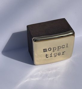 Den Künstler Jan M. Petersen arbeitet hier mit Cortenstahl und Bronze vergoldet. Geprägte Schrift: moppeltieger