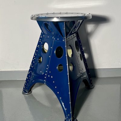 Das Projekt Aero 1946 kombiniert die Handwerksarbeit nach dem klassischen Flugzeugbau der 1940er Jahre mit dem Prinzip des Upcyclings. Das Material stammt in der Regel von Heckauslegern, Finne oder Elevatoren alter BELL-Hubschrauber. Die ultraleichten Hocker sind stylische Unikate und sehr belastbar. Die unterschiedlichen Farben, Beschriftungen und Nietlöcher verweisen auf die ursprüngliche Verwendung. Jeder Hocker ist auf der Unterseite mit dem passenden Typenschild versehen.