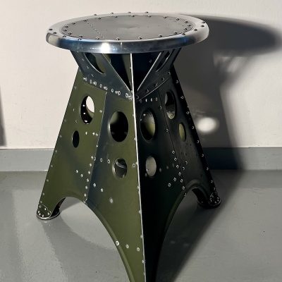 Das Projekt Aero 1946 kombiniert die Handwerksarbeit nach dem klassischen Flugzeugbau der 1940er Jahre mit dem Prinzip des Upcyclings. Das Material stammt in der Regel von Heckauslegern, Finne oder Elevatoren alter BELL-Hubschrauber. Die ultraleichten Hocker sind stylische Unikate und sehr belastbar. Die unterschiedlichen Farben, Beschriftungen und Nietlöcher verweisen auf die ursprüngliche Verwendung. Jeder Hocker ist auf der Unterseite mit dem passenden Typenschild versehen.